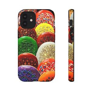 Puede incluir: Una colorida funda de teléfono con un patrón de diseños circulares decorativos con incrustaciones de joyas en varios colores. La funda tiene un recorte de cámara negro y un perfil lateral negro a juego, que muestra los intrincados detalles.