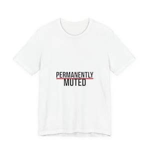 Puede incluir: Camiseta blanca con la frase "PERMANENTLY MUTED" en negro, con una línea roja que cruza la palabra "MUTED". El diseño es sencillo y audaz, adecuado para uso casual.