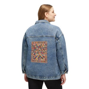 May include: A light blue denim jacket with a colourful, patterned patch on the back. The patch features a geometric design with various colours including red, yellow, blue, and green. The jacket has a classic button-up design.