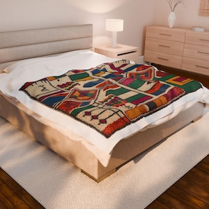 May include: A colorful, patterned blanket with a geometric design is draped over a bed. The blanket features a variety of colors, including red, green, blue, and orange. The bed is made up with a white sheet and a beige bed frame.