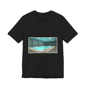 Könnte beinhalten: Schwarzes T-Shirt mit einem rechteckigen Grafikmotiv, das ein Hallenbad mit türkisfarbenem Wasser zeigt. Das Becken hat eine Leiter und ist von einem hellen Deck umgeben. Das Bild enthält Datum und Uhrzeit in der unteren rechten Ecke.