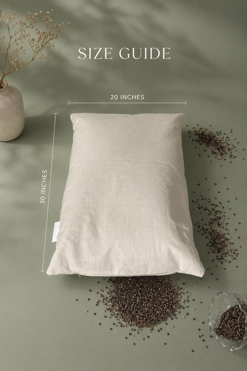 May include: A rectangular beige pillow with a visible fabric texture. The image includes the text SIZE GUIDE, 20 INCHES, and 30 INCHES, indicating the dimensions of the pillow. Small dark grains are scattered around the pillow on the surface.
