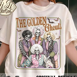 Könnte beinhalten: Ein cremefarbenes T-Shirt mit einem Grafikdruck von vier Skeletten mit stilisierten Frisuren und bunten gemusterten Blazern. Der Text lautet THE GOLDEN GHOULS, begleitet von kleinen Fledermaus- und Sternillustrationen in einem dünnen Rahmen.