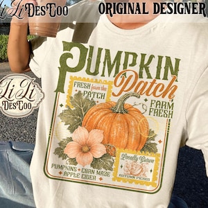 May include: A cream-colored t-shirt featuring a graphic print of an orange pumpkin, a light orange flower, and green leaves. The text reads PUMPKIN Patch, FRESH form the PATCH, FARM FRESH, LOCALLY GROWN, AUTUMN PICKED, PUMPKINS, CORN MAZE, and APPLE CIDER.