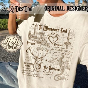 May include: Cream-colored t-shirt featuring a detailed graphic design with text and illustrations. The design includes a castle, a deer with antlers, a heart, a sword, and a dragon. The text includes "To Whatever End" and "The Thirteen".