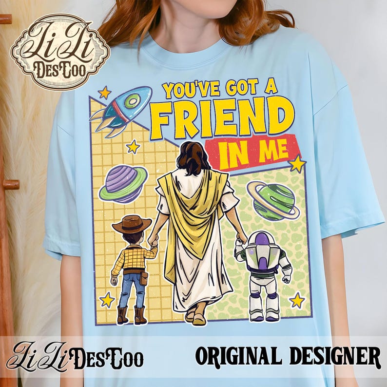 Puede incluir: Camiseta azul claro con un dise&ntilde;o gr&aacute;fico. El dise&ntilde;o incluye el texto "YOU'VE GOT A FRIEND IN ME", un cohete, planetas y personajes de dibujos animados. La camiseta tambi&eacute;n tiene el texto "ORIGINAL DESIGNER".