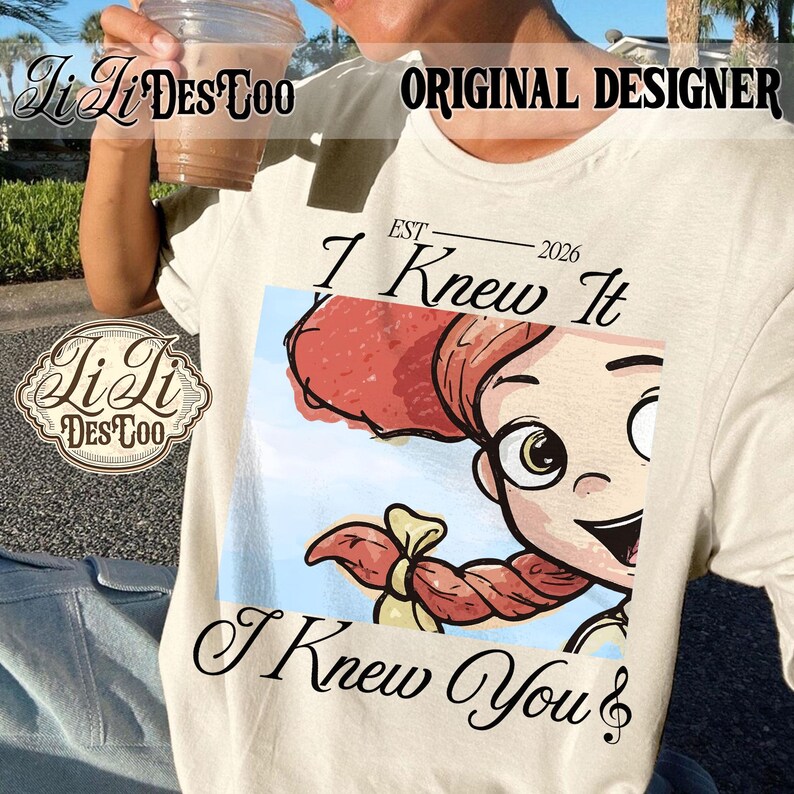 K&ouml;nnte beinhalten: Ein cremefarbenes T-Shirt mit einer Grafik einer Zeichentrickfigur mit roten Haaren im Pferdeschwanz. Der Text lautet "EST 2026", "I Knew It" und "I Knew You" mit einer Musiknote. Das Design ist auf der Vorderseite des Shirts zentriert.