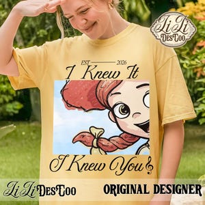 K&ouml;nnte beinhalten: Ein gelbes T-Shirt mit kurzen &Auml;rmeln und einer Grafik einer Zeichentrickfigur mit roten Haaren und einem Zopf. Der Text lautet EST 2026, I Knew It und I Knew You. Das Design enth&auml;lt ein Logo in der oberen rechten Ecke mit Li Li DES TOO.