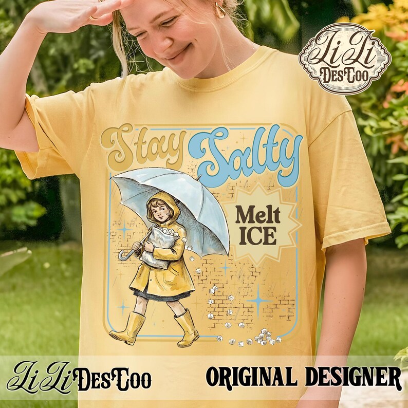 Pode incluir: Camiseta amarela mostarda com as palavras "Stay Salty" e um gr&aacute;fico de uma menina de capa de chuva e botas amarelas segurando um guarda-chuva. A camisa tamb&eacute;m tem as palavras "Melt ICE" e "Original Designer".