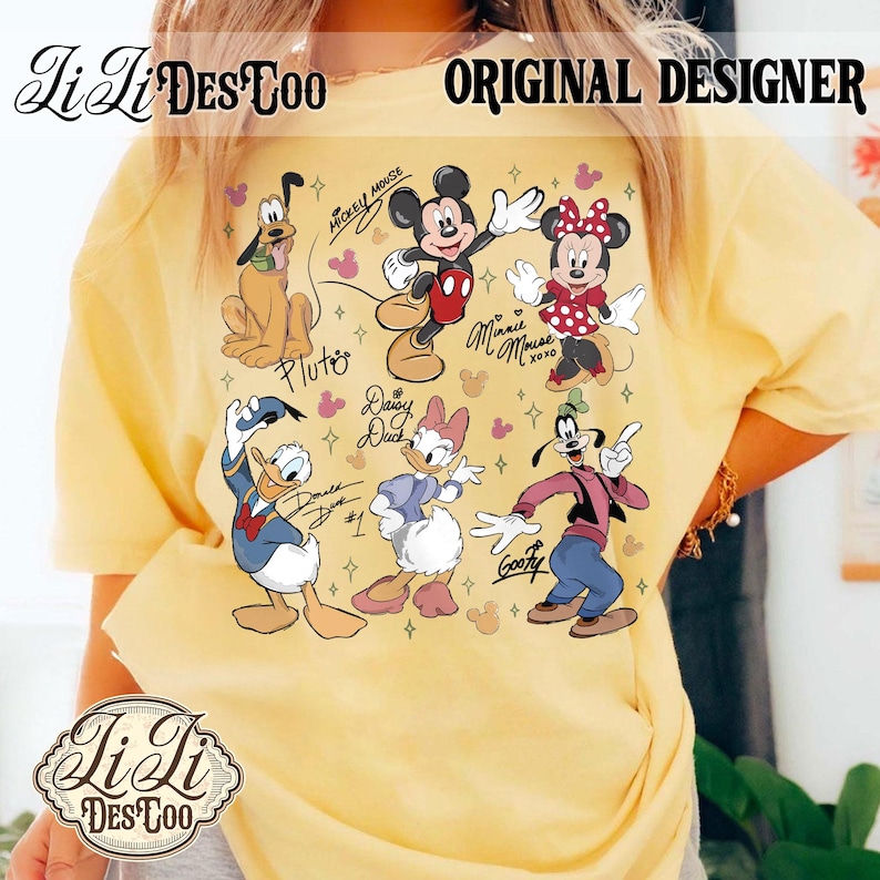 Puede incluir: Camiseta amarilla con un gr&aacute;fico colorido de personajes de Disney, incluyendo Mickey Mouse, Minnie Mouse, Pluto, Donald Duck, Daisy Duck y Goofy. La camiseta tiene el texto "Li Li Des Too" y "Original Designer".