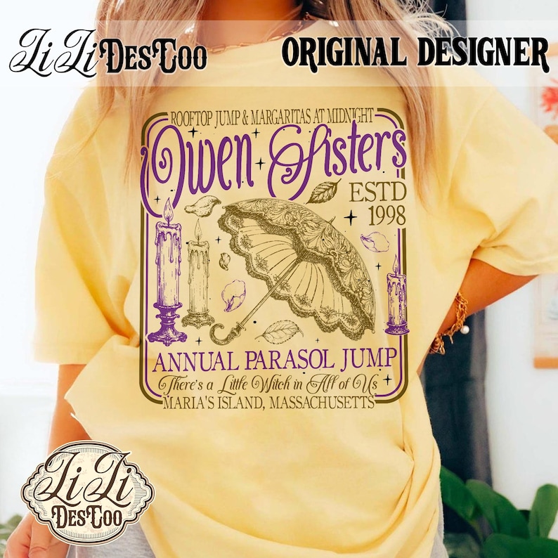 May include: A pale yellow t-shirt featuring a graphic print with purple and brown ink. The design includes an ornate parasol, three lit candles, and text reading "Owen Sisters ESTD 1998", "Annual Parasol Jump", and "There's a Little Witch in All of Us".