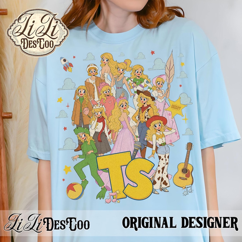 May include: A light blue t-shirt featuring a graphic print of multiple blonde characters in various outfits, including a green dinosaur costume, a cowgirl ensemble, and a space suit. The design includes a large yellow TS logo, a guitar, and a ball.