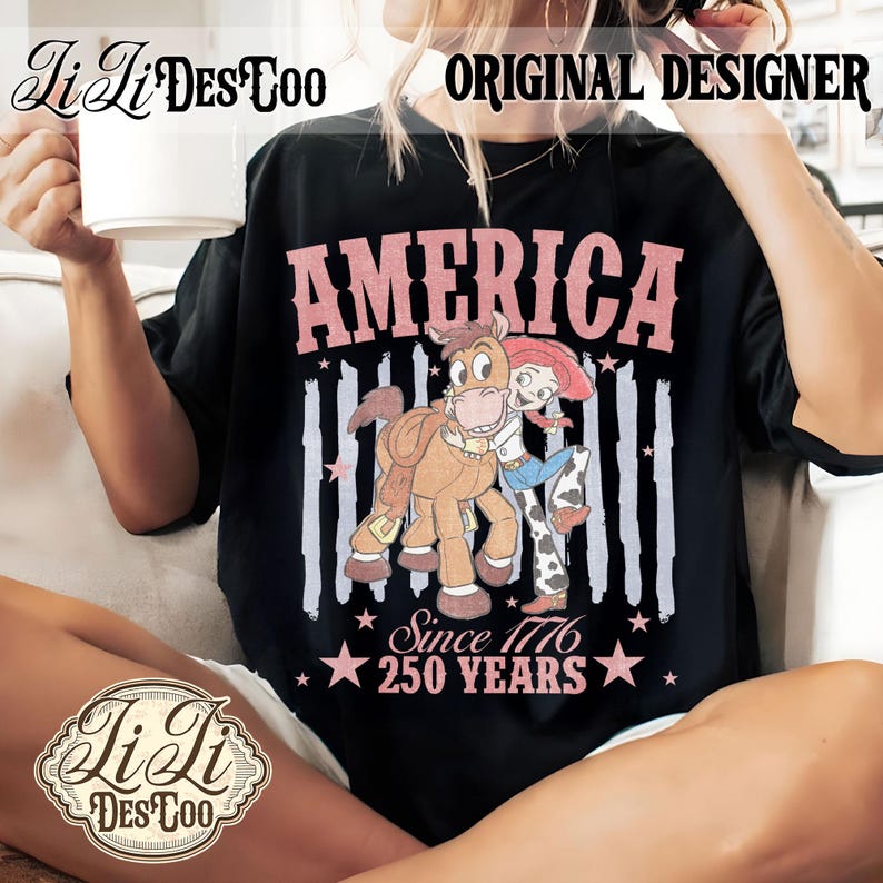 May include: A black t-shirt featuring a graphic of a cartoon cowgirl hugging a horse. The text reads AMERICA, Since 1776, and 250 YEARS in pink lettering. The design includes vertical distressed stripes and star accents, creating a patriotic theme.