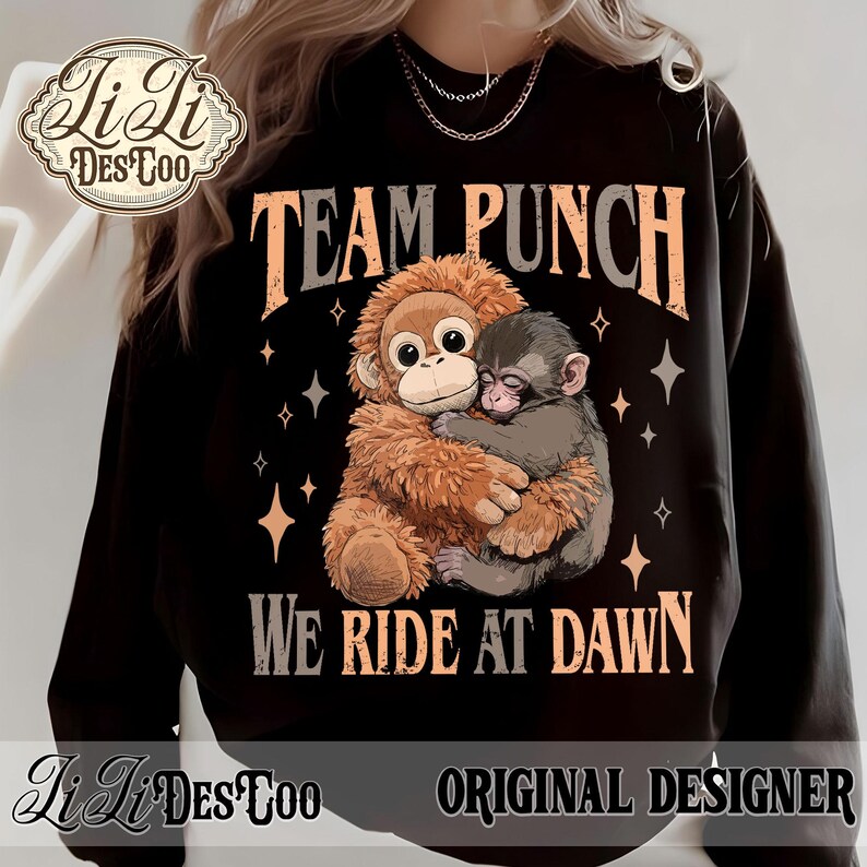 May include: Black sweatshirt with the text "TEAM PUNCH" and "WE RIDE AT DAWN". The design features two cartoon monkeys hugging, with star accents. The sweatshirt has the "Li Li DesCoo" logo and "ORIGINAL DESIGNER" text.