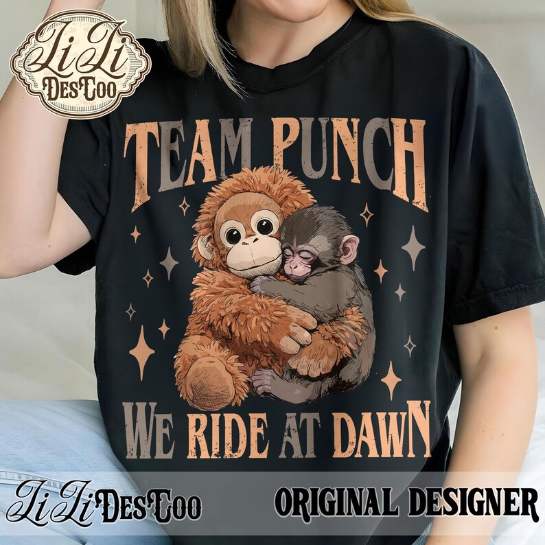 May include: Black t-shirt featuring a graphic of two monkeys hugging, with the text "TEAM PUNCH" above and "WE RIDE AT DAWN" below. The design includes star accents and the words "ORIGINAL DESIGNER".