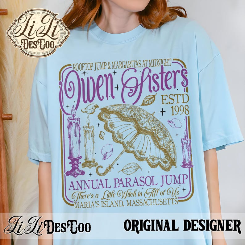 May include: A light blue t-shirt featuring a graphic print with the text "Rooftop Jump & Margaritas at Midnight", "Owen Sisters", "ESTD 1998", "Annual Parasol Jump", "There's a Little Witch in All of Us", and "Maria's Island, Massachusetts" with candles and a parasol.