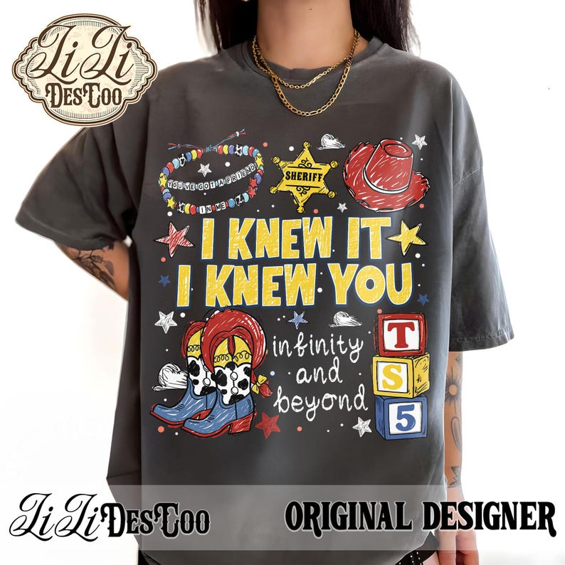 Op de afbeelding: Een antracietgrijs t-shirt met een grafische print van een sheriffster, een rode cowboyhoed, laarzen met koeienprint en kleurrijke blokken. De tekst luidt I KNEW IT I KNEW YOU, infinity and beyond en YOU'VE GOT A FRIEND IN ME.