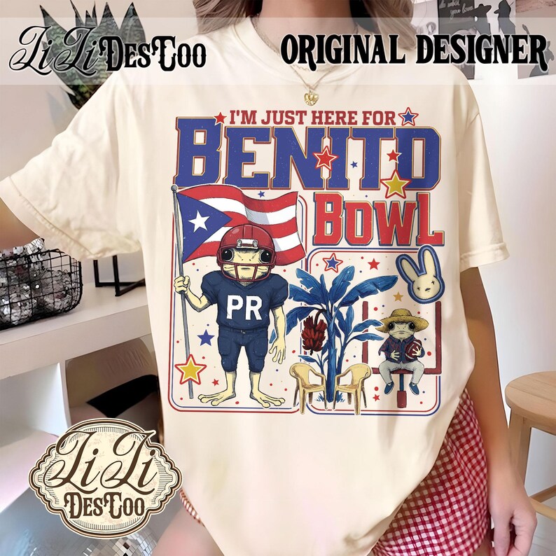 May include: Cream-colored t-shirt with a graphic featuring a frog in a football uniform holding a Puerto Rican flag. Text reads "I'M JUST HERE FOR BENITO BOWL" in blue and red. The shirt has the "Li Ji Des Too" logo.