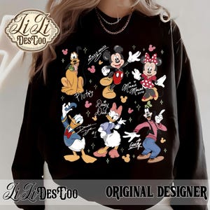 Puede incluir: Sudadera negra con un gr&aacute;fico colorido de personajes de Disney, incluyendo Mickey y Minnie Mouse, Pluto, Donald y Daisy Duck, y Goofy. El dise&ntilde;o incluye los nombres de los personajes y los textos "Mickey Mouse" y "Minnie Mouse xoxo."