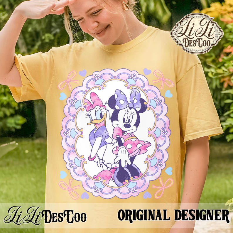 May include: Yellow t-shirt featuring a colorful graphic of Minnie Mouse and Daisy Duck inside a decorative frame with bows and hearts. The shirt has the text "Li Li DesCoo" and "ORIGINAL DESIGNER".