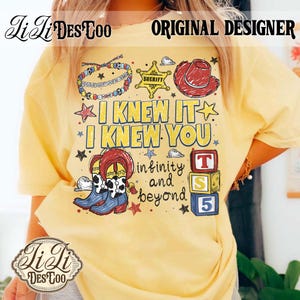 Op de afbeelding: Een lichtgeel t-shirt met een grafische print van een kralenarmband, een gele sheriffster, een rode cowboyhoed en een paar cowgirl-laarzen. De tekst luidt I KNEW IT I KNEW YOU en infinity and beyond, vergezeld door drie gestapelde alfabetblokken.