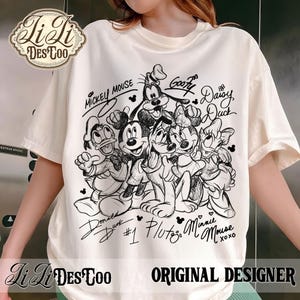 May include: Cream-colored t-shirt featuring a black and white illustration of Mickey Mouse, Minnie Mouse, Donald Duck, Daisy Duck, Goofy, and Pluto. The names of the characters are written above and below them. The shirt also has the text "LiLi DesToo" and "Original Designer".