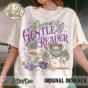 May include: Cream-colored t-shirt with a purple and green graphic. The graphic includes the text "Dearest Gentle Reader", a carriage, teacup, book, and flowers. The shirt also features the text "Li Li DesToo" and "Original Designer".