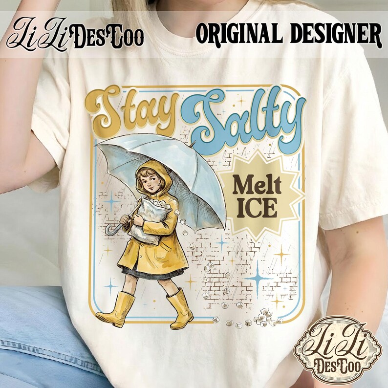 Pode incluir: Camiseta creme com um gr&aacute;fico retr&ocirc;. Apresenta uma menina de capa e botas amarelas sob um guarda-chuva, com as palavras "Stay Salty" e "Melt ICE". O design tem uma est&eacute;tica vintage.