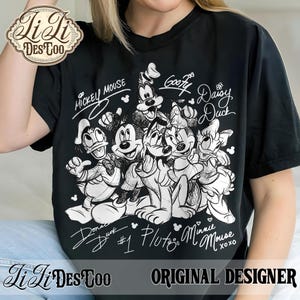 May include: Black t-shirt featuring a group of Disney characters, including Mickey Mouse, Goofy, and Donald Duck, in a black and white sketch design. The names of the characters are written above and below them. The shirt also has the text "Original Designer".