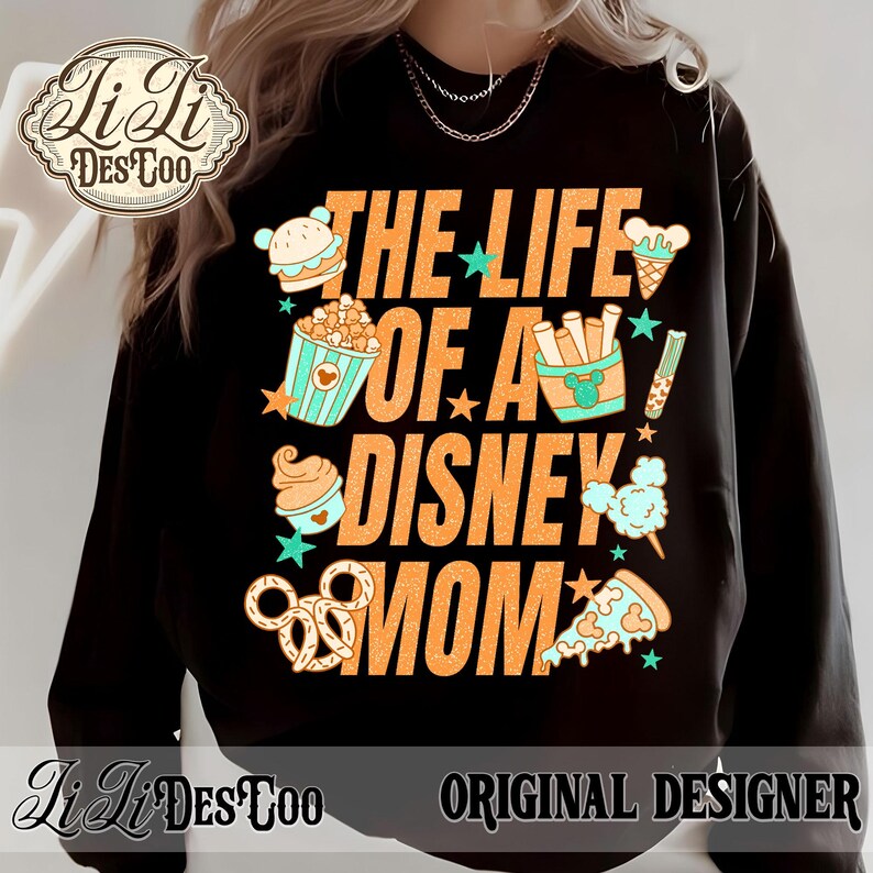 May include: Black sweatshirt with the text "THE LIFE OF A DISNEY MOM" in orange. The design includes cartoon images of a burger, popcorn, ice cream, fries, cotton candy, pizza, and pretzels. The sweatshirt has the "Li Li DesToo" logo.