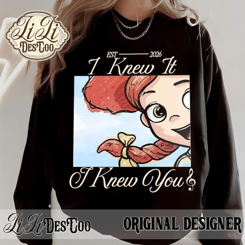 K&ouml;nnte beinhalten: Ein schwarzes Langarm-Sweatshirt mit einem Grafikdruck einer Zeichentrickfigur mit roten Haaren in einem Zopf. Der Text lautet EST 2026, I Knew It und I Knew You. Das Design enth&auml;lt ein Logo in der oberen linken Ecke mit LiLi DES TOO.
