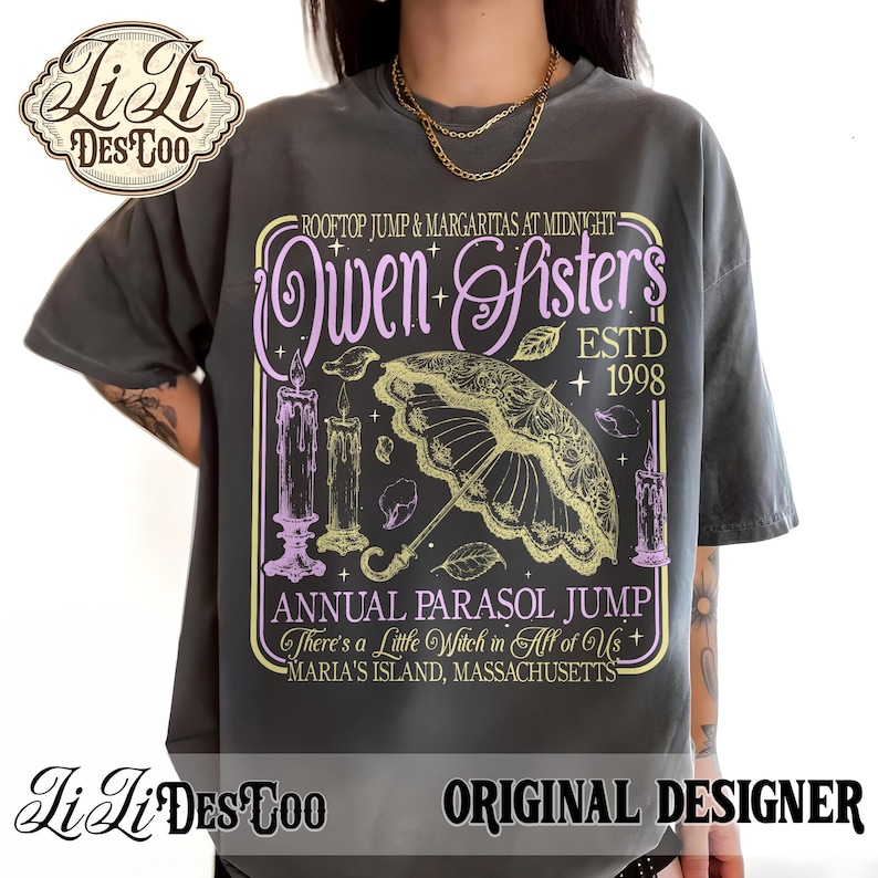 May include: A charcoal gray t-shirt featuring a graphic print with the text "Owen Sisters", "Rooftop Jump & Margaritas at Midnight", "Estd 1998", "Annual Parasol Jump", "There's a Little Witch in All of Us", and "Maria's Island, Massachusetts".