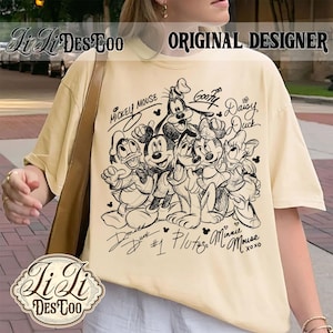 May include: Cream-colored t-shirt featuring a black and white illustration of Mickey Mouse, Minnie Mouse, Donald Duck, Daisy Duck, Goofy, and Pluto. The shirt has the text "Mickey Mouse" and character names. The words "Original Designer" are also visible.