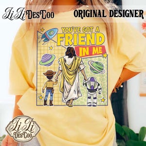 Puede incluir: Camiseta amarilla con la frase "YOU'VE GOT A FRIEND IN ME". El dise&ntilde;o incluye ilustraciones de un cohete, planetas y personajes de una pel&iacute;cula de animaci&oacute;n popular.
