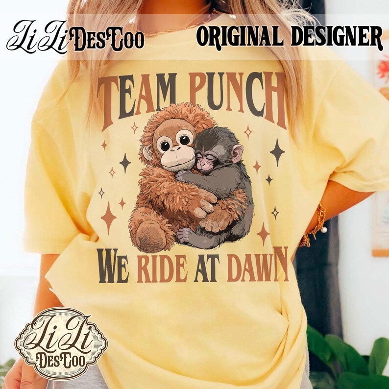 May include: Yellow t-shirt with a graphic of two hugging monkeys and the text "TEAM PUNCH WE RIDE AT DAWN." The design includes brown and black text and star accents. The shirt also has the text "Li Li Des Too" and "ORIGINAL DESIGNER."