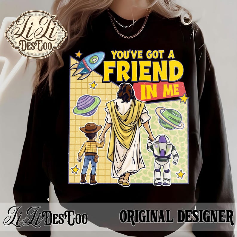 Puede incluir: Sudadera negra con un gr&aacute;fico colorido con el texto "YOU'VE GOT A FRIEND IN ME". El dise&ntilde;o incluye un cohete, planetas y personajes de dibujos animados. La sudadera tiene el texto "Li Li Des Too" y "ORIGINAL DESIGNER".
