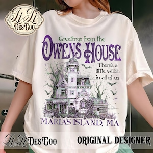 Peut inclure: Un t-shirt à manches courtes de couleur crème avec un motif représentant une maison de style victorien aux accents violets et verts. Le texte indique : Greetings from the OWENS HOUSE, There's a little witch in all of us, MARIA'S ISLAND, MA.