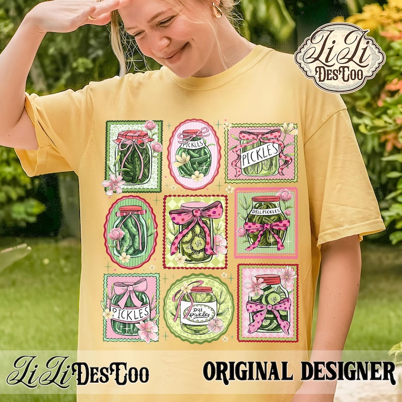 May include: Yellow t-shirt featuring a design of pickle jars with pink bows and floral accents. The jars are labeled "Pickles" and "Dill Pickles". The shirt also includes the text "Li Li Des Too" and "Original Designer".