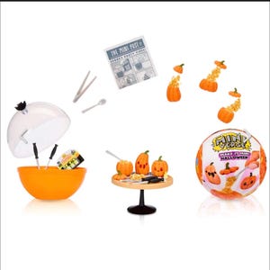 May include: An orange bowl with a clear lid, miniature utensils, and a small package. Several miniature pumpkins are arranged on a small table. A round ball with the text "Make It Mini Halloween" is also present.