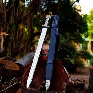 May include: A silver Viking sword with a black leather scabbard. The sword has runes engraved on the blade and a silver pommel. The scabbard has a silver tip and a black leather strap.