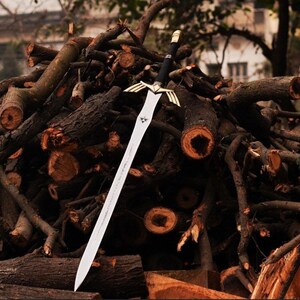 May include: A silver sword with a gold hilt and a black handle, resting on a pile of brown branches.