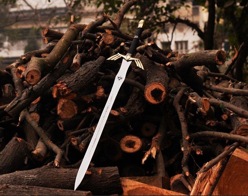 May include: A silver sword with a gold hilt and a black handle, resting on a pile of brown branches.