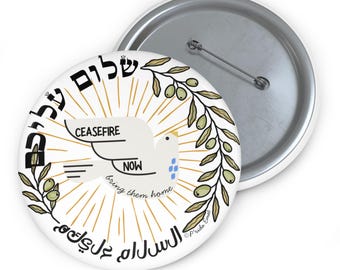 Könnte beinhalten: Ein weißer Knopf mit einer Taube, die die Worte "CEASEFIRE NOW bring them home" in schwarzer Schrift trägt. Die Taube ist von Olivenzweigen und den Worten "שלום עליכם" und "السَّلاَمُ عَلَيْكُمْ" in Hebräisch und Arabisch umgeben.