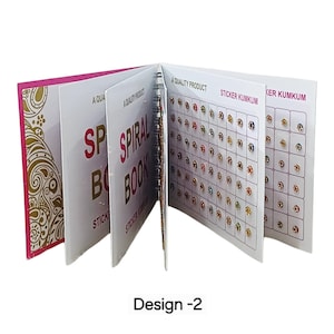 May include: A spiral-bound book containing multiple pages of adhesive sticker kumkum. The cover features gold paisley patterns on a pink background. The interior pages display grids of small, colorful, circular decorative stickers with the text A QUALITY PRODUCT and STICKER KUMKUM printed on the pages. The text Design -2 is visible below the book.