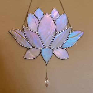 Peut inclure: Une fleur de lotus en vitrail aux p&eacute;tales iris&eacute;s dans les tons de blanc, de bleu et de violet. La fleur est soulign&eacute;e d'argent et est suspendue &agrave; une cha&icirc;ne. Une petite cha&icirc;ne avec des perles pend du bas.