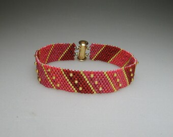 Pulsera de cuentas de vidrio en tonos rojo mate y dorado brillante, tejida con la técnica peyote.