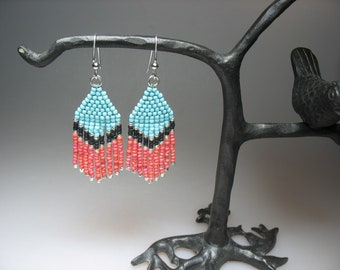 May include: A pair of turquoise, black and coral beaded earrings with silver hooks. The earrings are hanging from a black metal tree branch with a bird perched on the branch.
