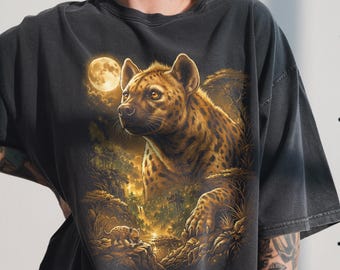 May include: Dark gray t-shirt featuring a detailed illustration of a hyena in a jungle setting under a full moon. The hyena has brown and black spots, with a smaller hyena in the foreground. The design has a vintage, worn look.