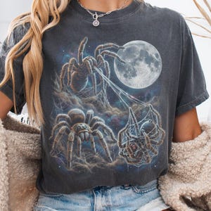 Vintage style three tarantulas moon graphic printed on dark washed t-shirt, hairy spider galaxy design spinning web.