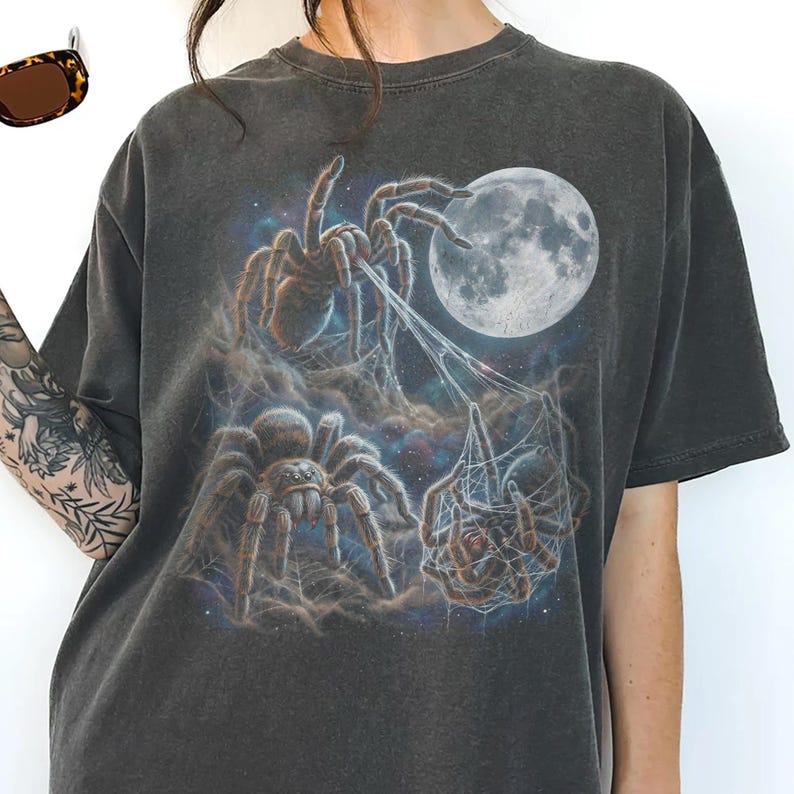 Vintage style three tarantulas moon graphic printed on dark washed t-shirt, hairy spider galaxy design spinning web.